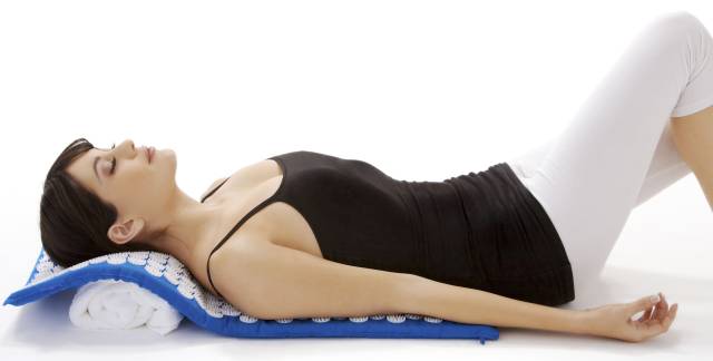 Lady lying on a blue acupressure mat